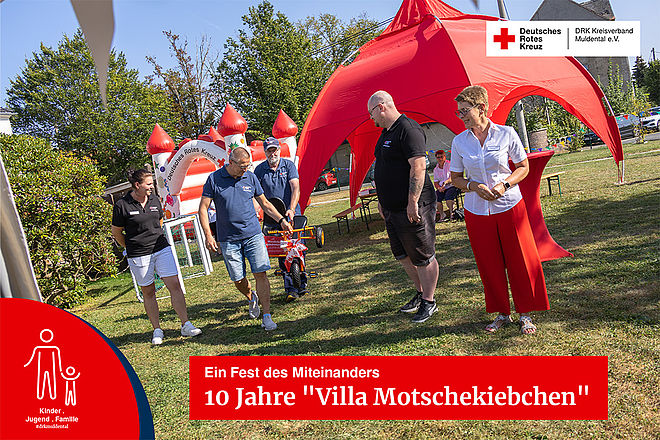 Spielende Kinder und Erwachsene bei einer Festrede auf dem Gelände des Kinderhaus "Villa Motschekiebchen" Falkenhain